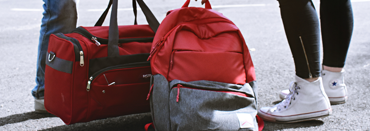 A close up shot of red luggage and a student's sneakers.