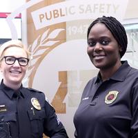 Sergeant Lange and Paida Chikate in front of the Department of Public Safety logo