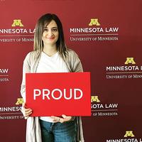 Shaghek Manjikian holding a "proud" sign in front of a Minnesota Law photo backdrop
